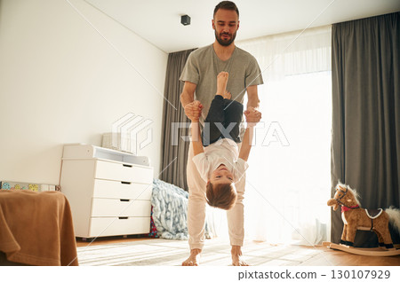 Playing, holding in hands. Man is playing with his little son in the domestic room 130107929