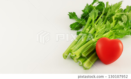 Healthy food concept. Green celery with red heart on white background with copy space. Vegetarian and vegan diet. Greens are good for heart health 130107952