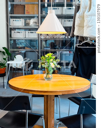 Round wooden table with vase of flowers inside cafe. Interior design, lifestyle, and social gathering. 130107979