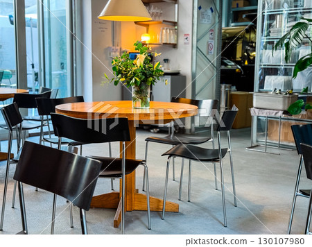 Cafe interior with wooden tables and glass shelves on wall. Urban lifestyle, hospitality, and social culture. 130107980