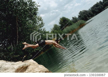 A young boy dives headfirst into the water on a summer day at the lake. Poland, Krzeszowek. 130108067