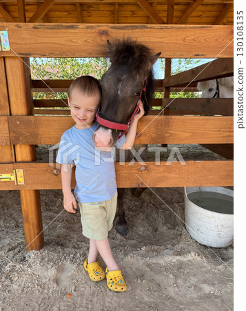Little boy hugging his beloved pony on the ranch 130108135
