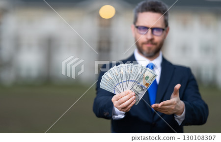 Businessman broker count money. Property concept. Successful realtor in suit with money dollar. House owner hold money outdoor. Realtor offering new home. Broker make offer, selective focus 130108307