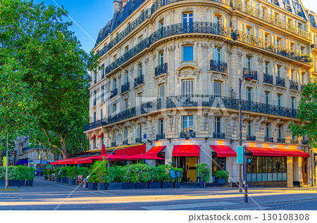 Paris city with street cafe restaurant on boulevard, traditional Parisian architecture apartment building with typical facade, balconies and windows iron fences in Le Marais historic district 130108308