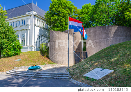 National Monument of Solidarity at Cannon Hill Kanounenhiwwel, Luxembourg flags on poles and green trees in Luxembourg city historical centre 130108343