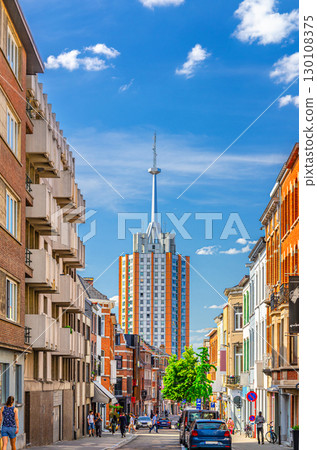 High residential building with spire and narrow street with parking cars in Leuven city center in sunny summer day, blue sky background, Flemish Region, Flemish Brabant province, Belgium High residential building with spire and narrow street with parking cars in Leuven city center in sunny summer day, blue sky background, Flemish Region, Flemish Brabant province, Belgium 130108375