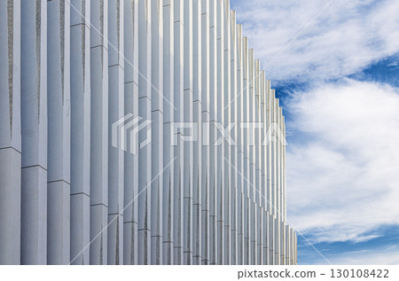 Patterned vertical stripes, columns structure of modern design building wall abstract details with cloudy blue sky background 130108422