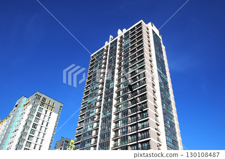 A very tall building stands against a clear blue sky backdrop A very tall building stands against a clear blue sky backdrop 130108487