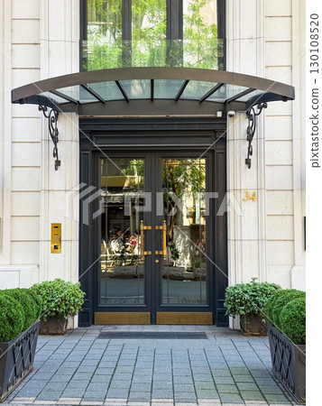 Elegant entrance door with glass and metal canopy. Concept of architecture, real estate, and urban lifestyle. 130108520