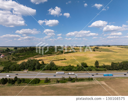 Trucks transporting goods on highway crossing fields and forests near Velke mezirici, Czechia, under partly cloudy sky Trucks transporting goods on highway crossing fields and forests near Velke mezirici, Czechia, under partly cloudy sky 130108575
