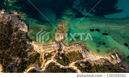 Aerial view of Toroni beach in Sithonia, Khalkidhiki, Greece, highlighting the crystal clear turquoise waters, beach umbrellas, and rocky coastline 130108581