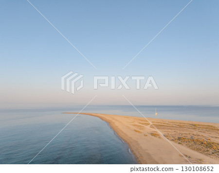 Breathtaking aerial view of a sailboat moored near a beautiful sandy spit in Khalkidhiki, Greece, as the sun rises, creating a serene and idyllic scene Breathtaking aerial view of a sailboat moored near a beautiful sandy spit in Khalkidhiki, Greece, as the sun rises, creating a serene and idyllic scene 130108652
