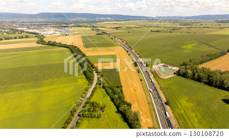 Aerial view of a highway cutting through farmland and fields near Tata, Hungary, showcasing transportation infrastructure amidst rural scenery 130108720
