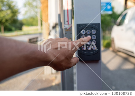Hand pushing a button on a security keypad, unlocking access to a door or gate, ensuring safety and control for private properties Hand pushing a button on a security keypad, unlocking access to a door or gate, ensuring safety and control for private properties 130108728