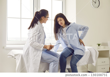 Pregnant woman feeling unwell suffering from backache during meeting with her doctor in clinic. 130108731
