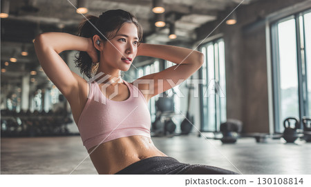 一名女子在健身房流汗並做腹部鍛煉 130108814