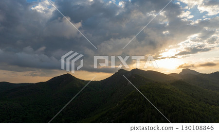 Sunbeams are filtering through a cloudy sky at sunset, illuminating the peaks of the mountains in Gilet, Spain Sunbeams are filtering through a cloudy sky at sunset, illuminating the peaks of the mountains in Gilet, Spain 130108846