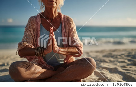 Mature woman doing yoga on a sandy beach with hands together in a meditative pose during sunset. Mature woman doing yoga on a sandy beach with hands together in a meditative pose during sunset. 130108902