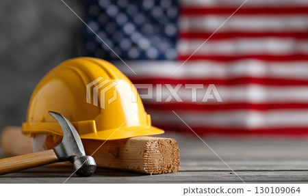 A yellow construction helmet and hammer on wooden block with American flag in background. Labor Day holiday in USA A yellow construction helmet and hammer on wooden block with American flag in background. Labor Day holiday in USA 130109064