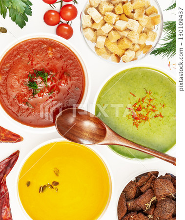 Food banner with set of different vegetable cream soups with wooden spoon on a white background with ingredients. Cozy meal, vegetarian healthy food. Top view Food banner with set of different vegetable cream soups with wooden spoon on a white background with ingredients. Cozy meal, vegetarian healthy food. Top view 130109437