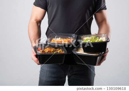 Man holding multiple takeout containers with a focus on healthy eating choices 130109618