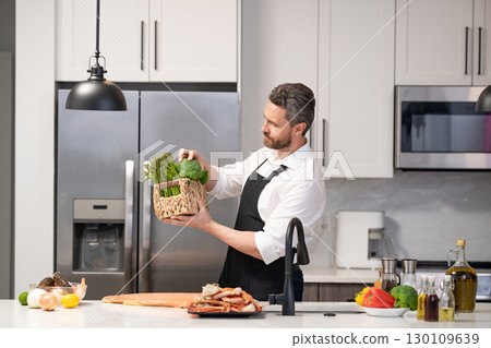 Man cook tasty meal. Home menu with seafood food. Man cook cooking at kitchen. Hispanic man standing in kitchen preparing sea food. Millennial man cook tasty crab leg. Healthy food diet 130109639