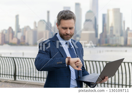 Businessman check time outdoor in NY. Business man getting late. Punctual man check time on wristwatch. Business meeting online deadline. Successful businessman checking time 130109711