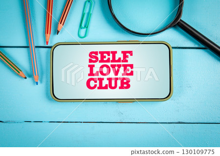 Self Love Club Message Displayed on Smartphone with Stationery on Blue Wooden Background Self Love Club Message Displayed on Smartphone with Stationery on Blue Wooden Background 130109775