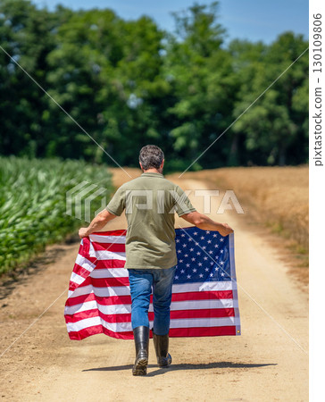 Flag of USA. Independence day. Man in field. Man with American flag in crop field. Independence day of America. 4th July. American labor day. American flag and man farmer. Freedom colors 130109806