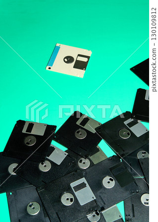 A collection of obsolete floppy disks, artifacts from the digital age of the 90s, arranged haphazardly on a turquoise background 130109812