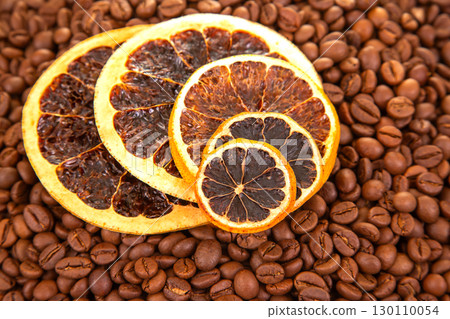 A vibrant close-up of dried orange slices nestled among roasted coffee beans 130110054