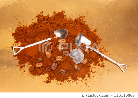 Close-up of two metal shovels in ground coffee, featuring whole beans 130110062