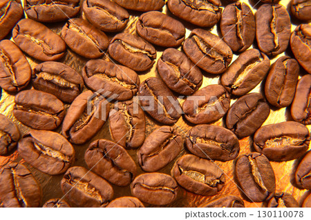 Close-up of roasted coffee beans on a golden tray 130110078