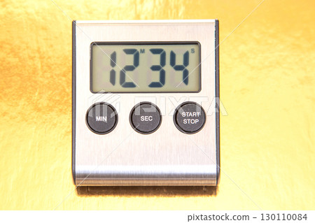 A sleek digital kitchen timer displays 12:34 on a bright yellow background. A sleek digital kitchen timer displays 12:34 on a bright yellow background. 130110084