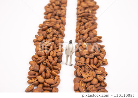 A metaphorical stock shot of a small figure in a suit between coffee beans A metaphorical stock shot of a small figure in a suit between coffee beans 130110085