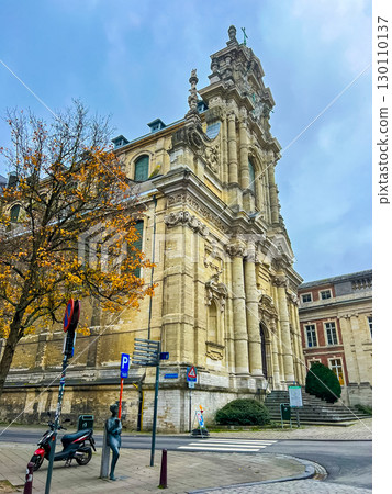 Victorian gothic church in Leuven with beige stone facade under blue sky 130110137