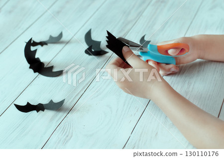 a child's hands cut out paper bats, Halloween 130110176