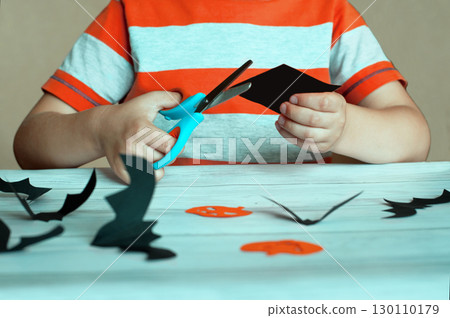 Halloween concept, child cuts out pumpkin and bat figurines from paper Halloween concept, child cuts out pumpkin and bat figurines from paper 130110179