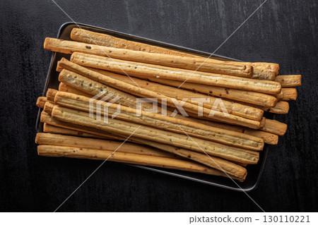 Crispy grissini breadsticks on plate on black table. Top view. Crispy grissini breadsticks on plate on black table. Top view. 130110221