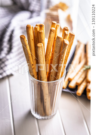 Crispy grissini breadsticks in cup on white table. 130110224