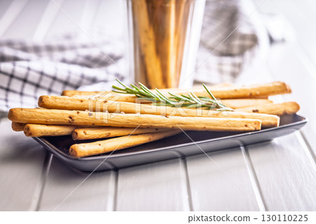 Crispy grissini breadsticks on plate on white table. 130110225
