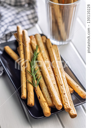 Crispy grissini breadsticks on plate on white table. 130110226