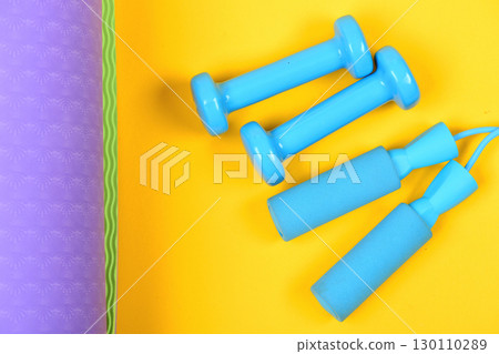 Shaping and fitness. Barbells and skipping rope on yoga mat 130110289