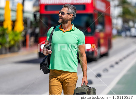 Traveler suitcase for summer trip. Man booking summer trip. Hispanic tourist traveler book online outdoor. Tourist with travel bag. Traveler using phone. Tourist booking vacation trip. Online tickets 130110537