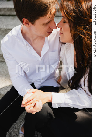 Young loving married couple sharing intimate moment on outdoor steps with natural light 130110560