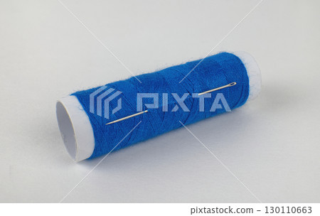 blue thread and needle on a white background. High quality photo 130110663