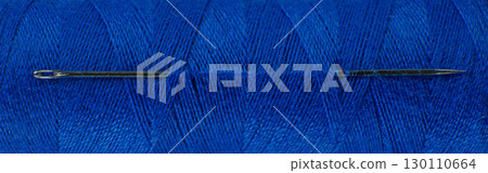 Close up view of a needle and blue thread for sewing. High quality photo 130110664