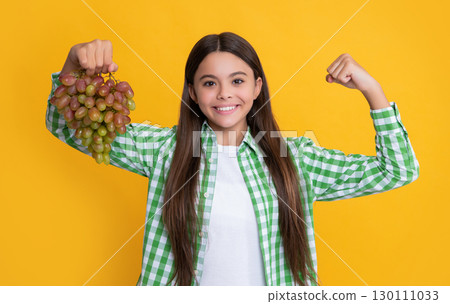cheerful child with grapes bunch on yellow background. diet 130111033
