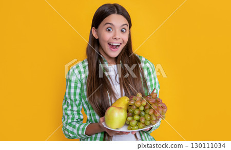 amazed teen child with fruit plate on yellow background 130111034