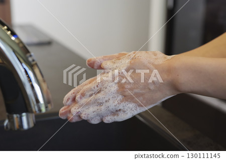 Woman washing her hands in the kitchen (no face) 130111145